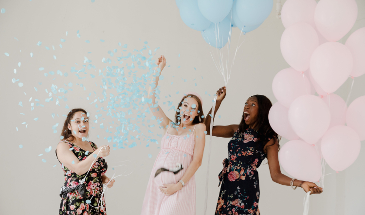 gender reveal ideas - pregnant woman popping balloon filled with blue confetti